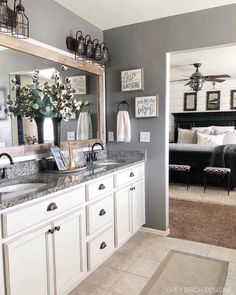 a bathroom with white cabinets and gray walls, along with a large mirror on the wall