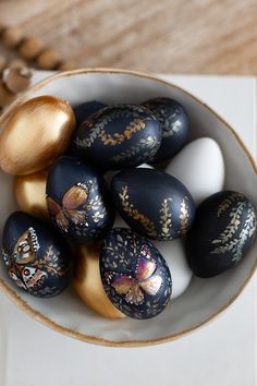 a bowl filled with painted eggs on top of a table