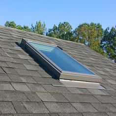 an open skylight on top of a shingled roof