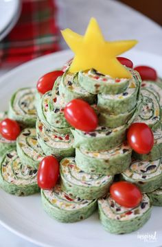 a white plate topped with green pastries covered in red and yellow toppings next to a star