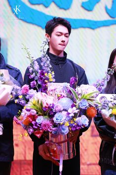 three people are holding flowers in their hands