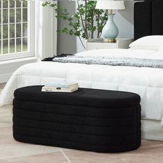 a bedroom with a large bed and black ottoman