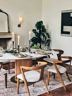 a dining room table is set with white chairs and place settings for two people to eat