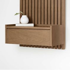 a white vase sitting on top of a wooden shelf next to a wall mounted shelf