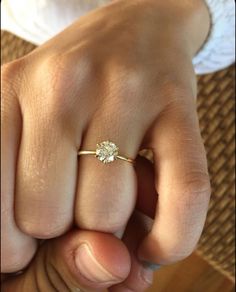 a close up of a person's hand with a diamond ring on their finger