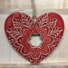 a red heart shaped ornament hanging on a wall