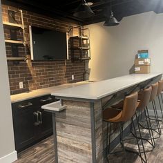 an empty bar with several stools in a room that has brick walls and wood flooring