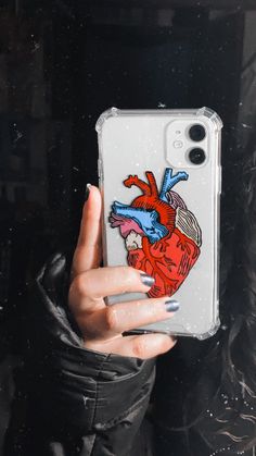 a woman holding up her phone case with an image of a human heart on it