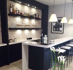 a bar with stools and bottles on the shelves in a room that has white tile flooring