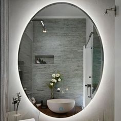 a bathroom with a large round mirror on the wall and a sink in front of it