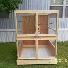 a wooden bird cage sitting in the grass