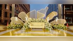 a stage set up for a wedding ceremony with flowers and butterfly wings on the backdrop