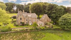 an aerial view of a large house in the middle of a lush green field with trees