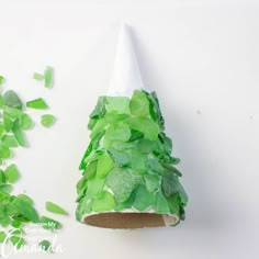 a paper cone shaped like a christmas tree with green leaves on the top and bottom