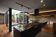 an open kitchen and dining area with wood floors, glass walls, and ceiling lights