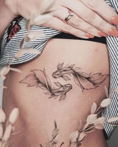 a woman's stomach with a fish tattoo on her belly and leaves around it