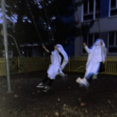 two people dressed in white are playing frisbee on the street at night time