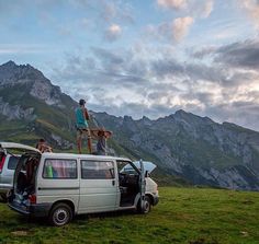 two men standing on the roof of a van