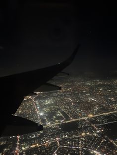 an airplane wing flying over a city at night