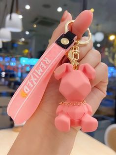 a person holding a pink keychain with an animal on it