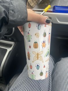 a person holding a cup in their hand with bugs all over it and a pencil sticking out of it