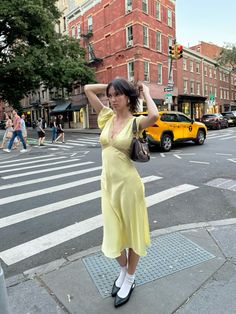 a woman in a yellow dress crossing the street