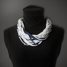 a white and blue necklace on top of a black mannequin headdress