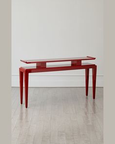 a red table sitting on top of a hard wood floor next to a white wall