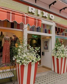 a store front with striped flower pots outside