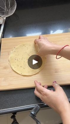 a person making food on top of a wooden cutting board