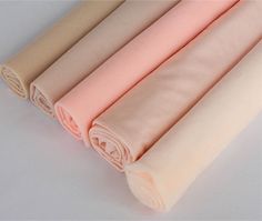 four different colors of fabric on a white tablecloth with one rolled up and the other folded down