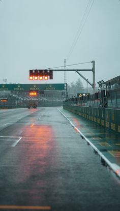 a traffic light that is on top of a pole in the rain and it's raining