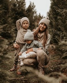 a woman and two children are sitting in the woods with their arms around each other