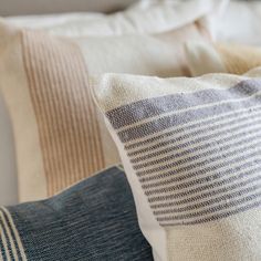 the pillows are all lined up on the bed together, and one is blue with white stripes