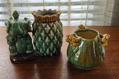 three small ceramic vases sitting on top of a wooden table next to each other