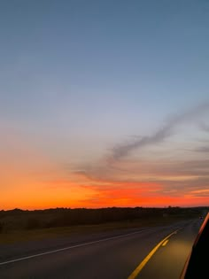 the sun is setting on an empty highway