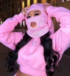 a woman with long hair wearing a pink hoodie and holding her head in front of her face