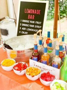 a table topped with bowls filled with fruit and drinks next to a sign that says lemonade bar