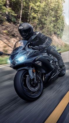 a person riding a motorcycle on a road with trees in the backgrouund