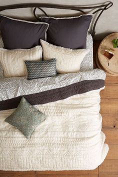 a bed with two pillows and one pillow on top of the headboard, next to a night stand