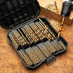 a black case filled with lots of wooden dows next to a pair of drillers