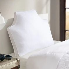 an unmade bed with white sheets and pillows on top of it next to a window