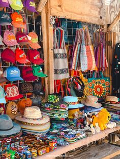 many hats and purses are on display in a market stall, including one for sale