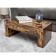 a wooden coffee table with a book on top and a mug next to it in front of a couch