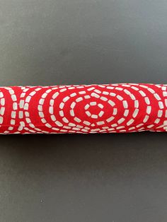 a red and white umbrella sitting on top of a gray table next to a black wall