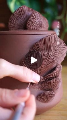 a person is painting the inside of a clay pot with chocolate colored yarn on it