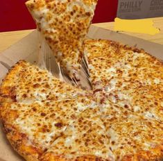 a pizza sitting on top of a cardboard box next to a slice of cheese pizza