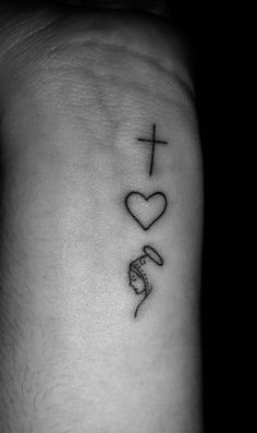 a cross, heart and snake tattoo on the left side of the arm is shown