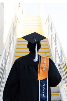 a man in graduation cap and gown walking up stairs