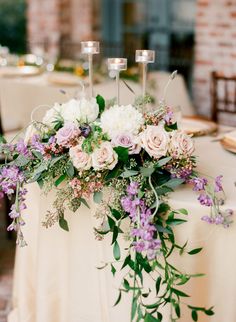 the table is set with candles, flowers and greenery for an elegant centerpiece